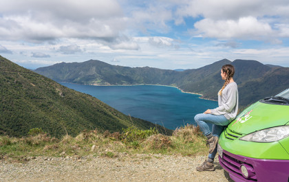 A girl looking at nature outside her JUCY campervan