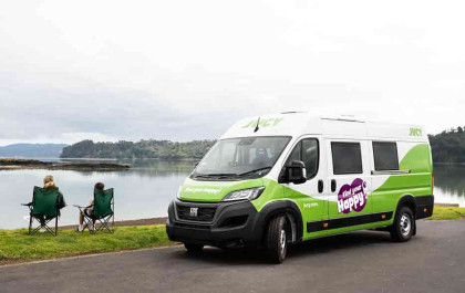 Two people on camping chairs outside cruiser campervan