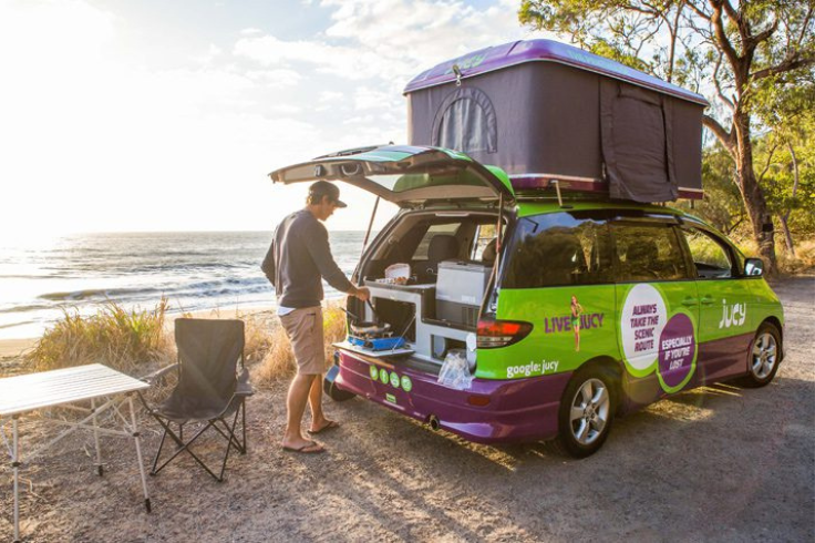 Male cooking in back of JUCY campervan kitchen