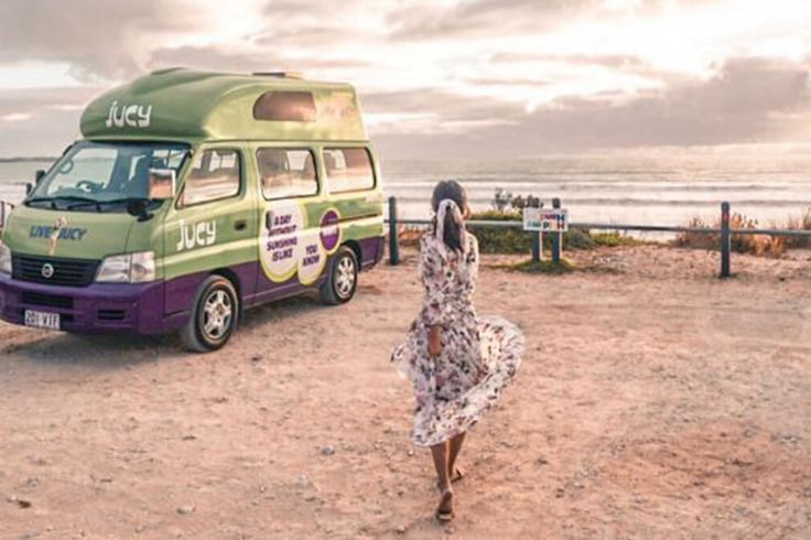 girl in sundress twirls in front of jucy vehicle