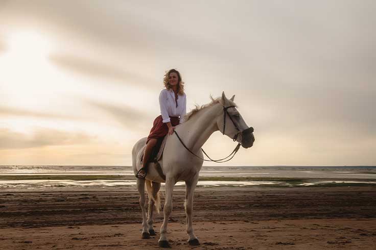 A woman on a horse at the beach