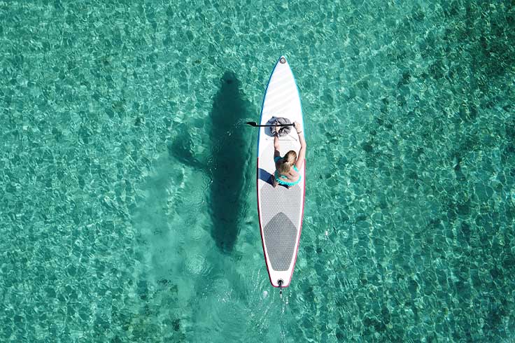 A woman in the middle of clear water ocean surfing