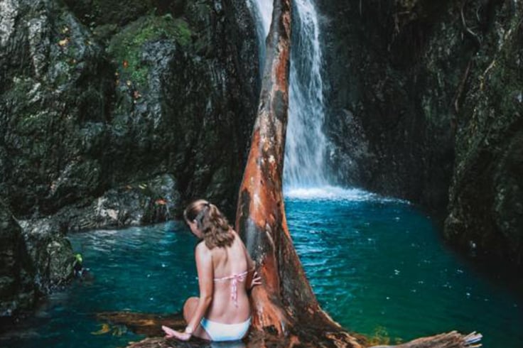 girl sits on a rock in front of fairy falls near cairns