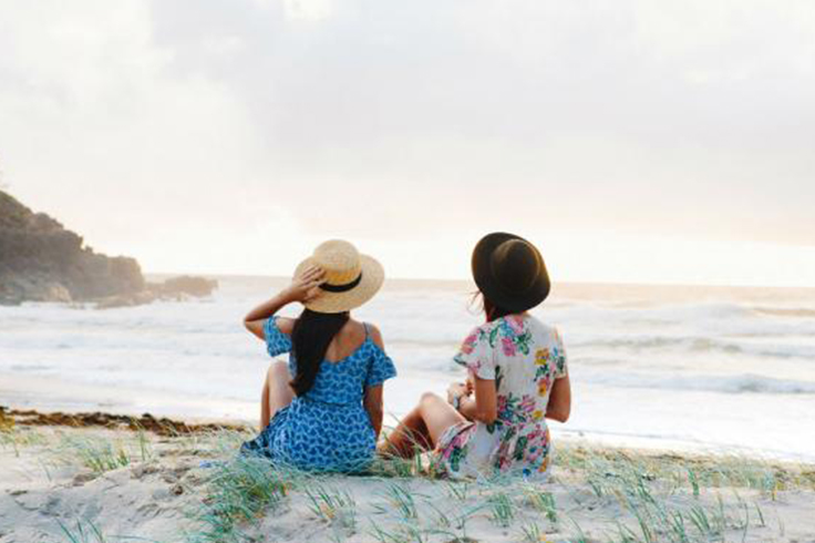 two girls sit on a beach on grand pacific drive