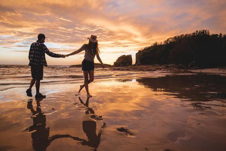 Couple walking along a beach at sunset