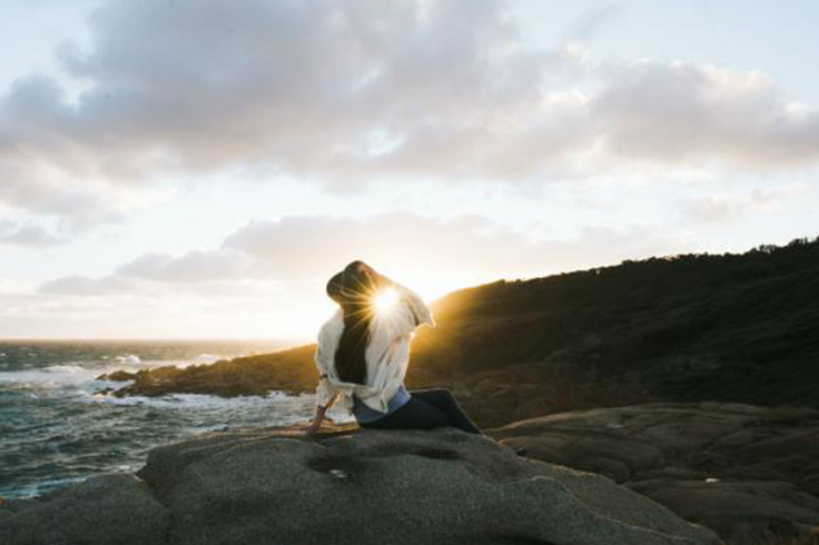 Girl sitting on a rock looking at a beach view at Wilsons Promontory National Park