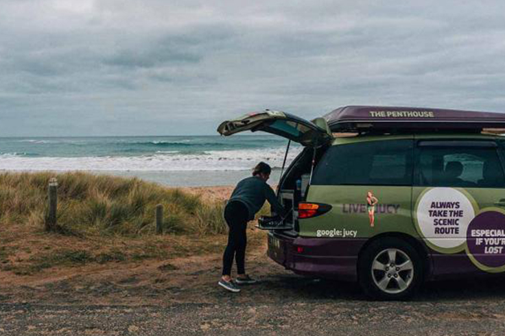 Person cooking in the back of a JUCY campervan