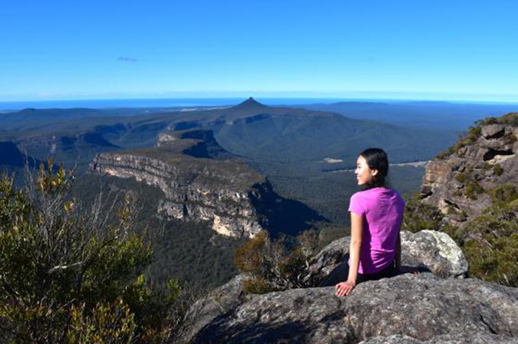 Girl looking out to a view at the top of a mountain