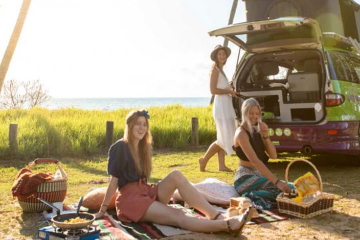 3 girls having a picnic and cooking with a JUCY campervan