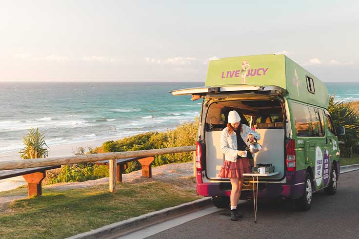 Girl pouring a coffee for herself at the back of a JUCY Condo Campervan