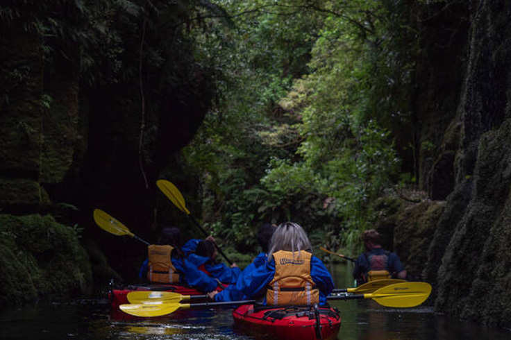 Couple of kayakers going into cave