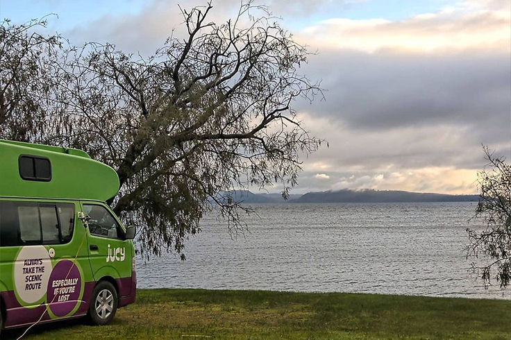JUCY Camper parked at campsite beside Lake Taupo