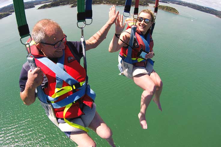 Father and daughter parasailing above Paihia (Bay of Islands))