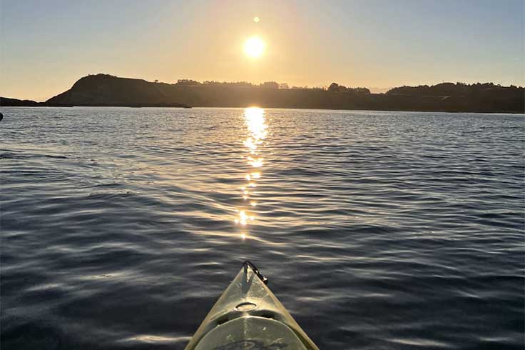 Kayak sitting on water facing sunset