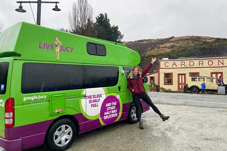 Girl beside JUCY Campervan parked in front of Cardrona Hotel