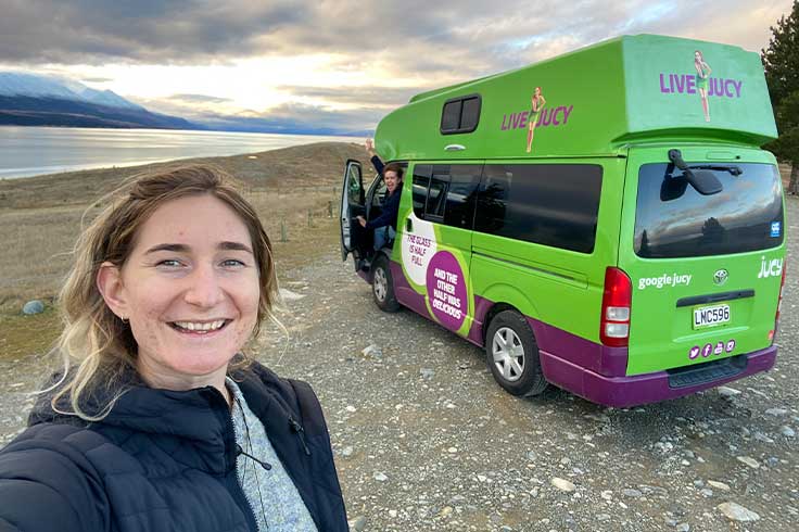 Girls posing in front of JUCY campervan