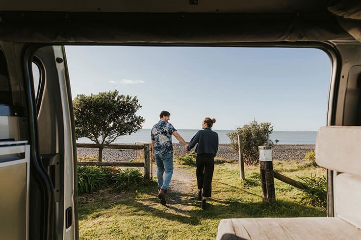 Couple walking away from campervan by beach