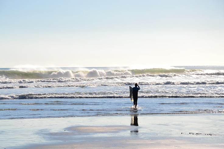 Surfer walking out to sea