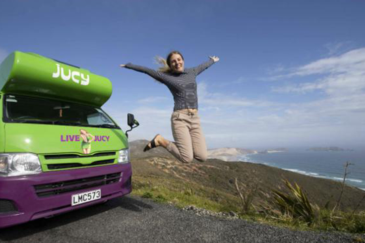 Girl jumping outside JUCY camper