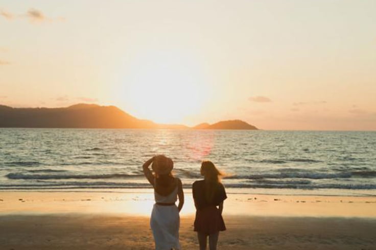 Two girls walking beach at sunset