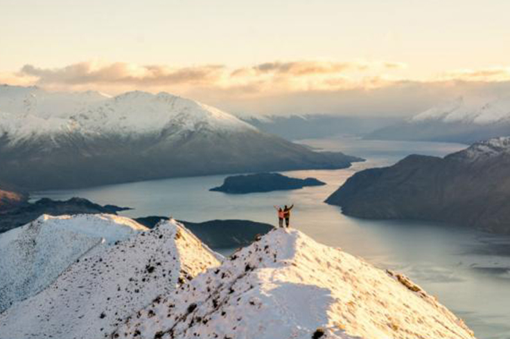 Two friends standing on top of a snowy mountain