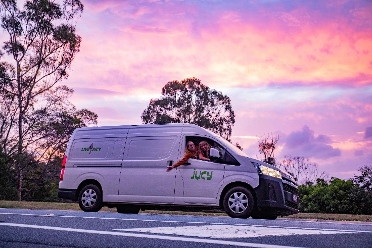 Two girls in a JUCY Campervan at sunset.