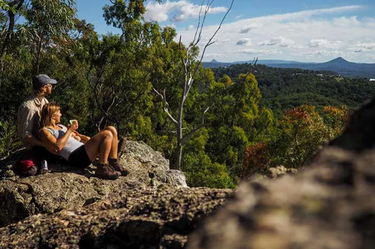 Couple after hike, looking out across top of forest