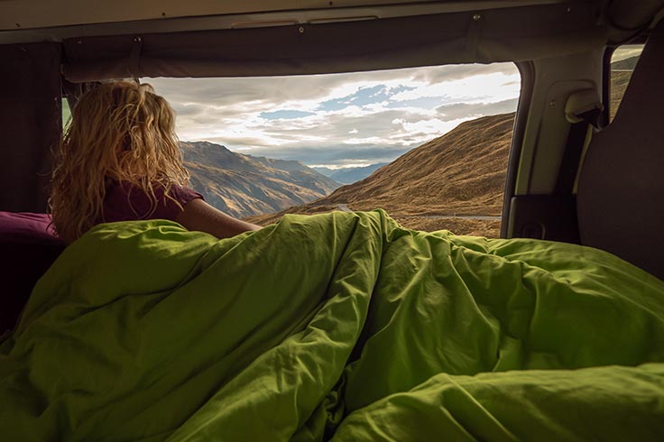 woman in blanket looks at distance from condo