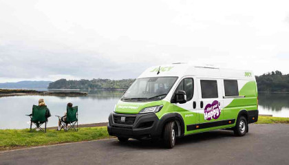 Two people on camping chairs outside cruiser campervan