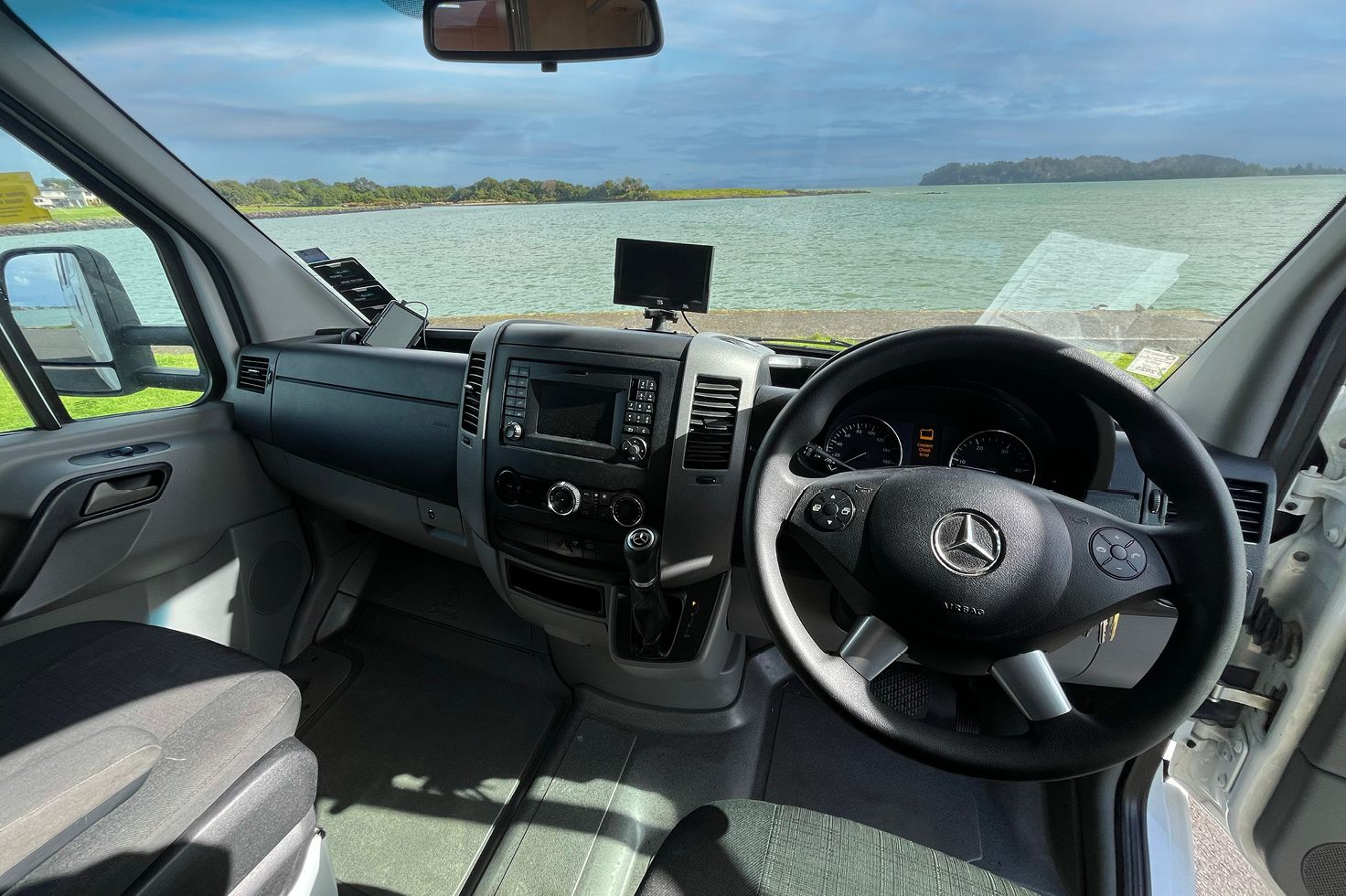 Interior cockpit view of a JUCY Big Kahuna motorhome with steering wheel, dashboard, and front seats.