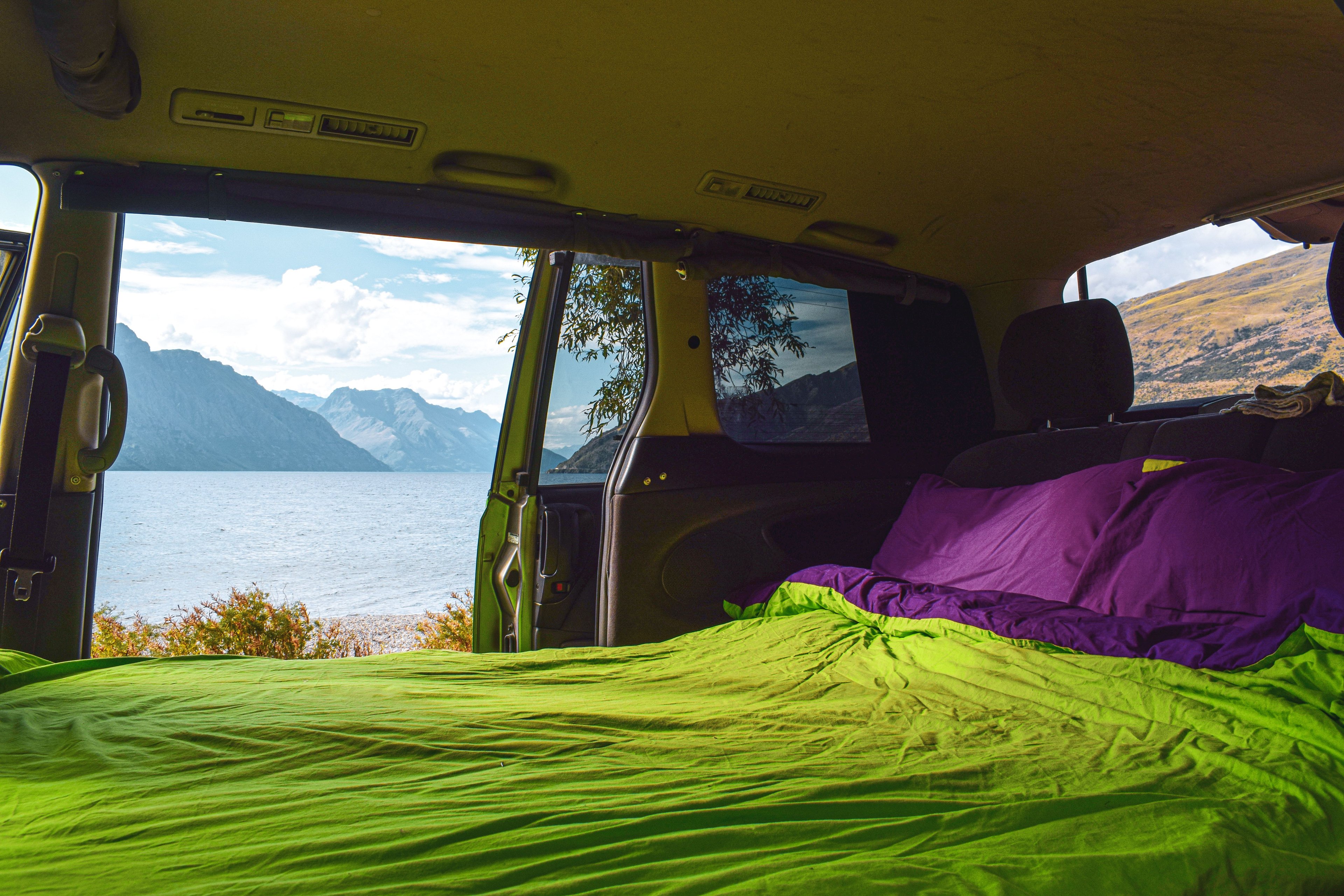 Interior of JUCY Crib Campervan with made bed at the lake 